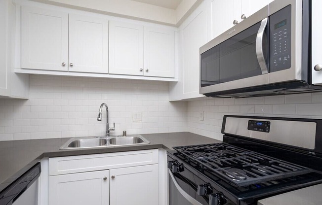 A modern kitchen with a black stove top oven and white cabinets.