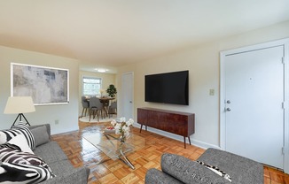 living area with sofa, coffee table, large windows, and view of dining areas at colonnade apartments in washington dc