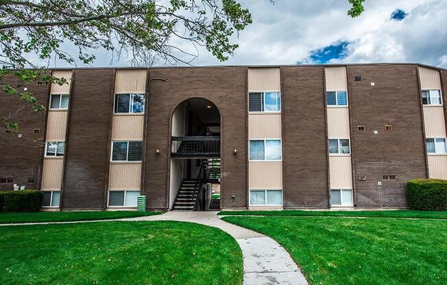 A large brick building with a green lawn in front.