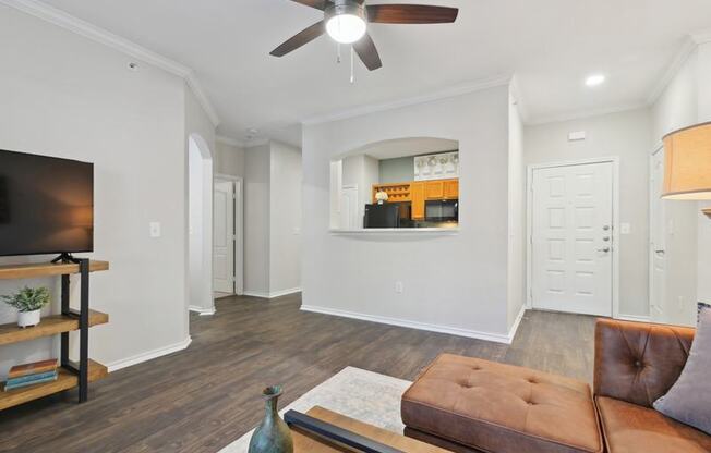A living room with a brown leather couch and a ceiling fan.