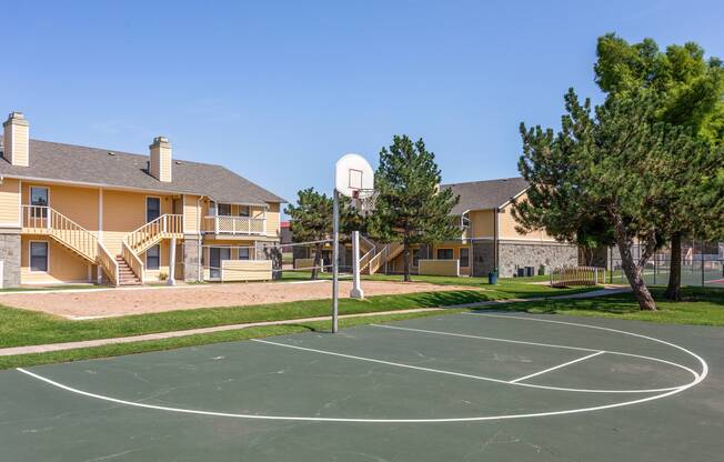 Outdoor basketball court next to sand volleyball court outside apartments