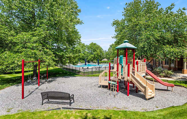 A playground with a slide, swings, and a bench.