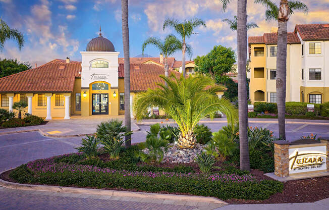 A beautifully landscaped entrance to a residential complex with a sign that reads "Tulumara".