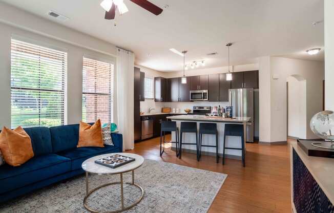 a living room with a couch and a table in front of a kitchen