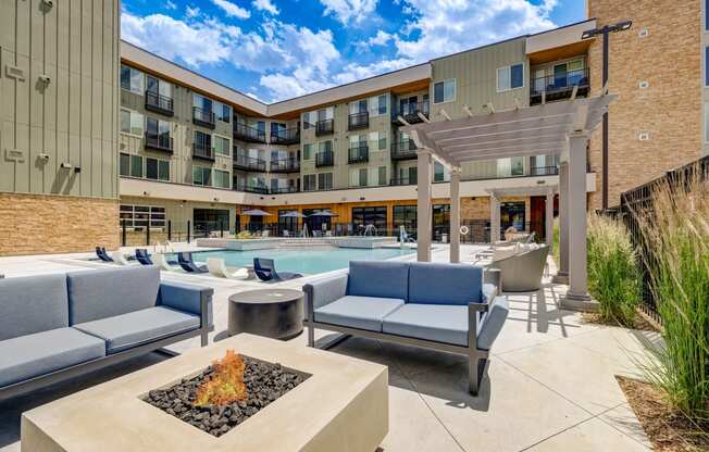 a patio with couches and chairs and a fire pit in front of a building