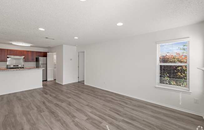 an empty living room and kitchen with a large window