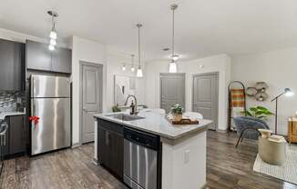 A modern kitchen with a stainless steel refrigerator and wooden flooring.