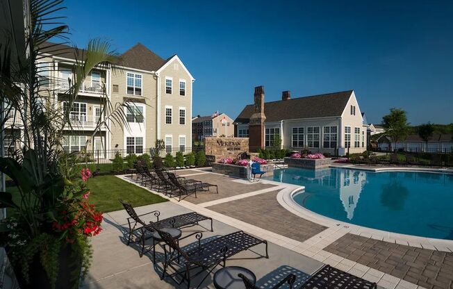 A pool area with lounge chairs and a building in the background.at Meridian West Shore, Mechanicsburg Pennsylvania