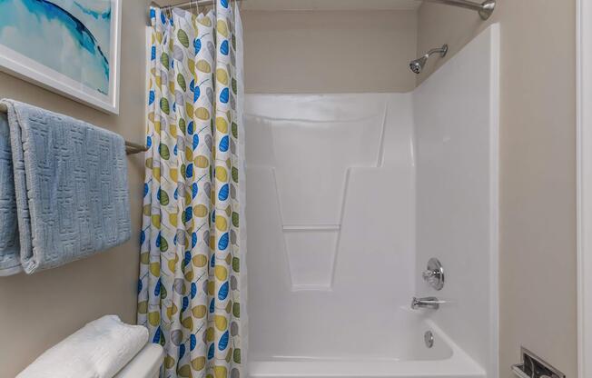 Bathtub with shower curtain in a bathroom at Ashley Oaks Apartments in Greensboro, North Carolina