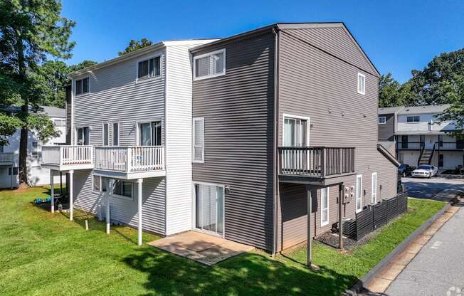 a gray house with two balconies on the side of a street