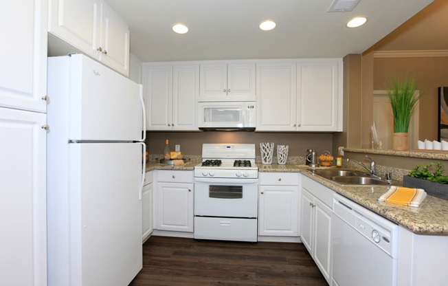 a kitchen with white cabinets and appliances and a counter top