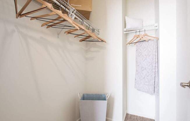A white wall with a wooden hanger and a white trash can.