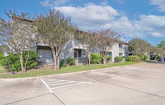 Surface parking lot in front of apartment buildings with a clear blue sky at Laurel Parc apartments in Shreveport, LA.