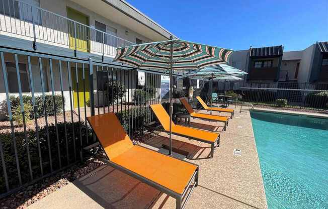 A row of sun loungers are on the edge of a pool.