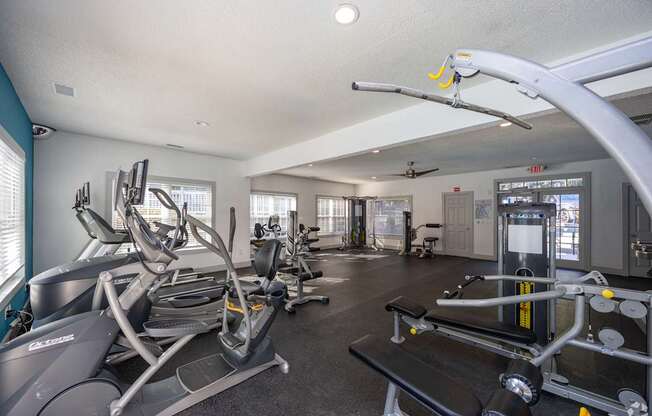A gym with a variety of equipment including treadmills, weights, and exercise machines.