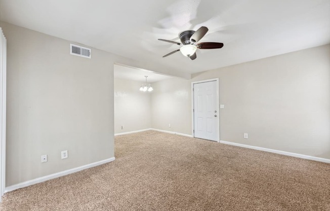 the spacious living room with ceiling fan and carpet