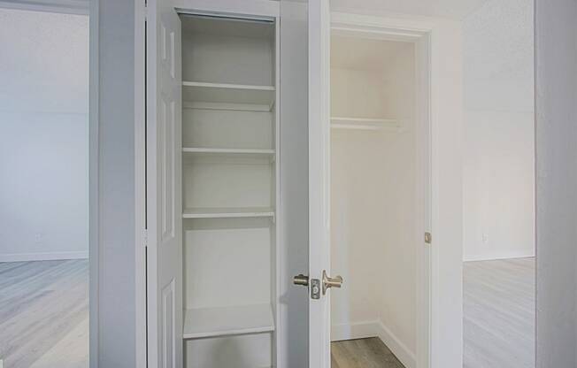 an empty room with white closet doors and a wood floor