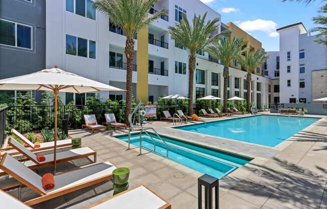 Swimming pool with lounge chairs and umbrellas in front of apartment building at Array La Mesa, La Mesa, CA