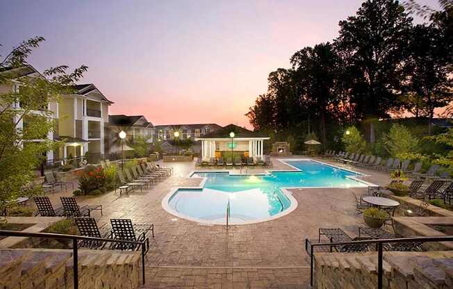 A swimming pool surrounded by a stone patio and lounge chairs.