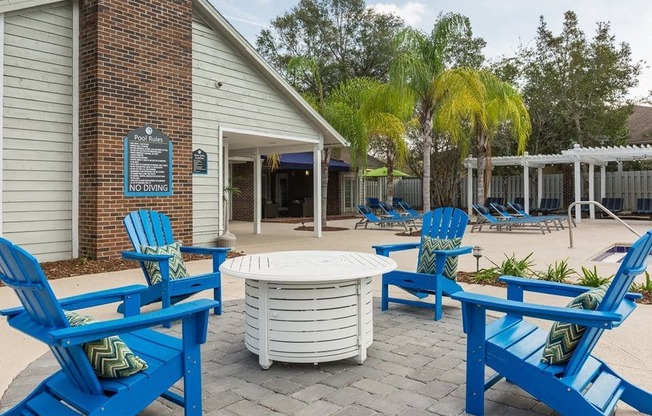 a patio with blue chairs and a table in front of a building