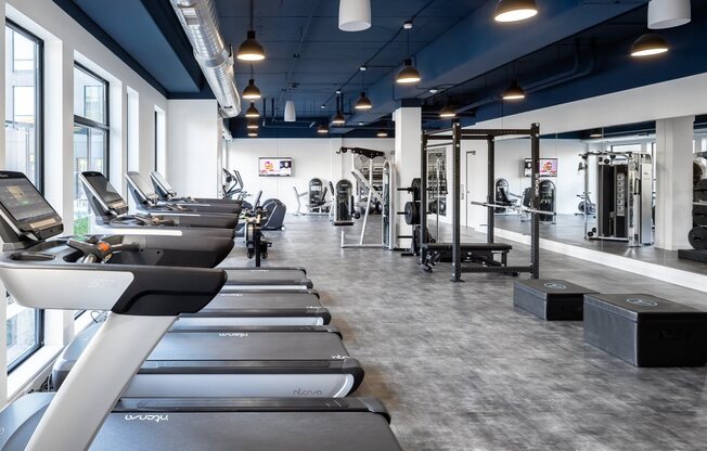 Treadmills and mirror in forefront of gym for apartment residents