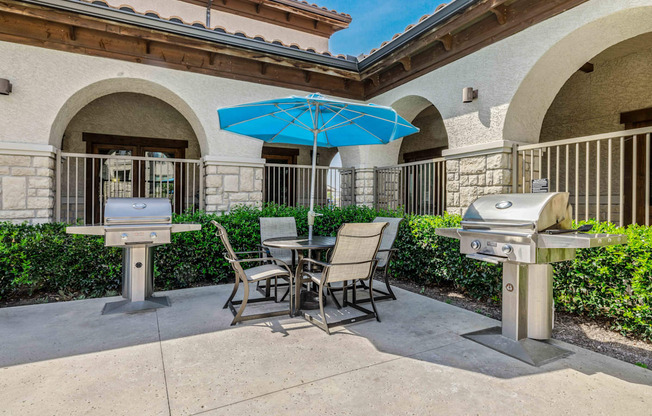 a patio with two bbq grills and a table and chairs