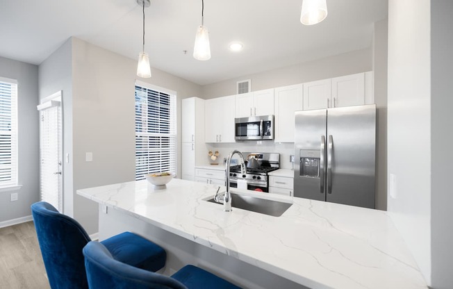 A modern kitchen with a white marble countertop and blue chairs at Harbor Pointe Apartments, Bayonne