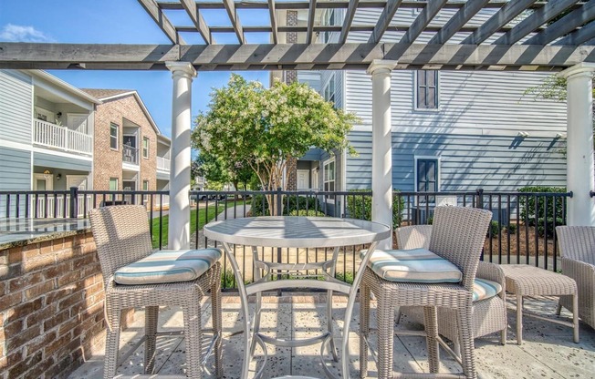 A patio with a table and chairs under a pergola.