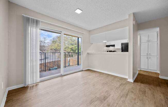 A spacious room with a sliding glass door leading to a balcony.