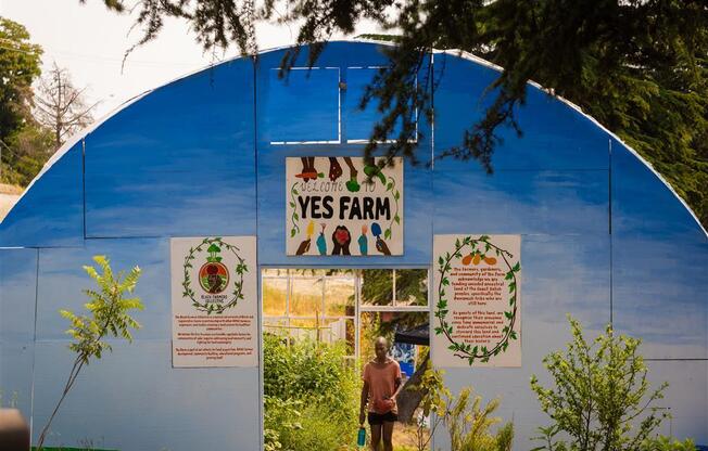 a woman walking through a greenhouse with a sign that says yes farm