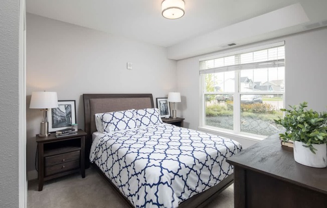 A bedroom with a bed, nightstand, and window.