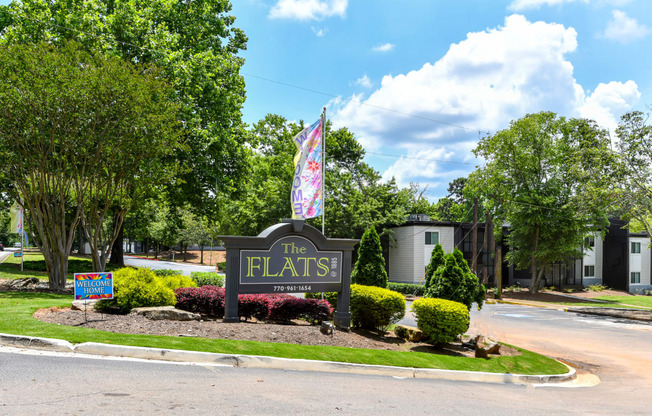 a sign that says the flats in front of trees and bushes