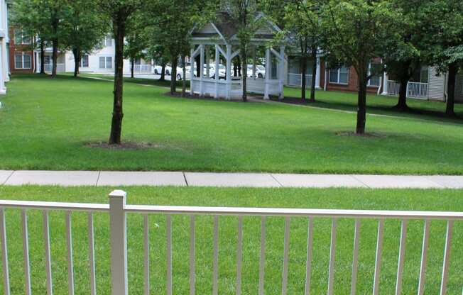 a patio with two chairs and a table on a porch overlooking a lawn