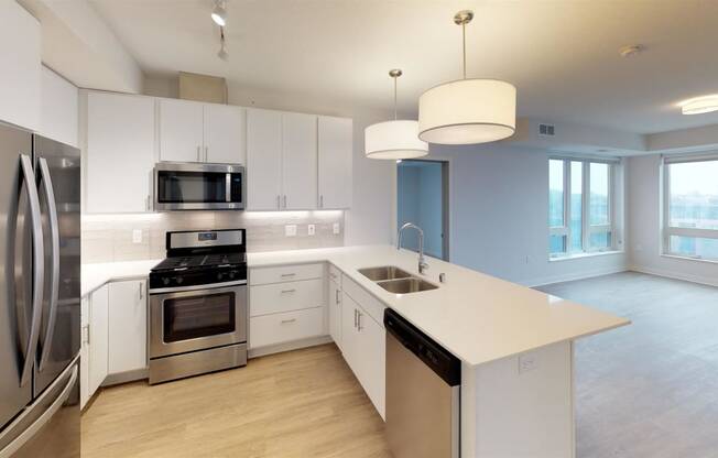 a white kitchen with stainless steel appliances and white counter tops