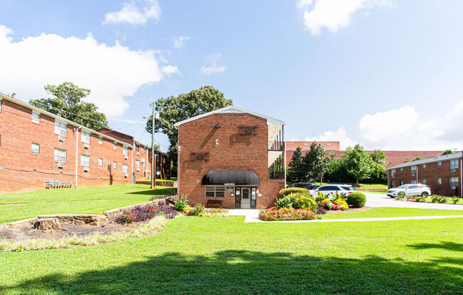 a brick building with a black awning in the middle of a grassy area