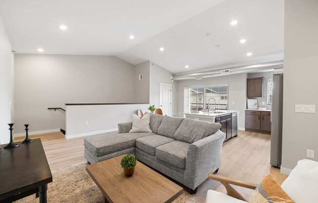 A modern living room with a grey sofa and a wooden coffee table.
