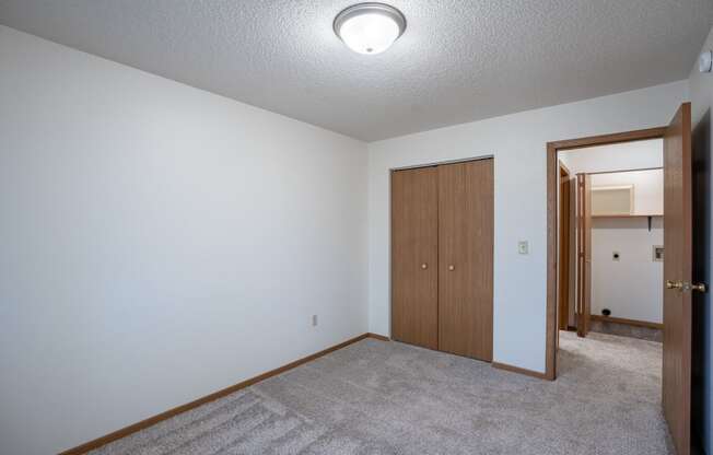 a bedroom with carpet and a door to a closet. Fargo, ND  Prairie Park Apartments
