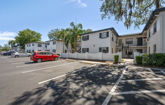 Charming apartment complex with well-maintained exterior, ample parking, lush greenery, and inviting entrances under clear blue skies.