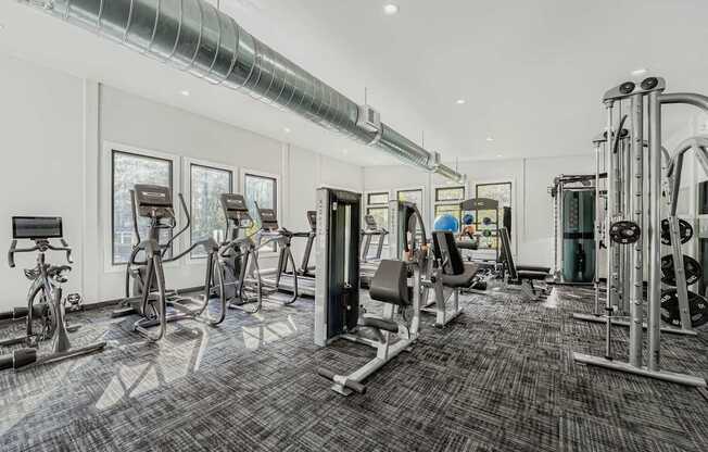 A spacious gym with a variety of equipment including treadmills, stationary bikes, and weight machines.