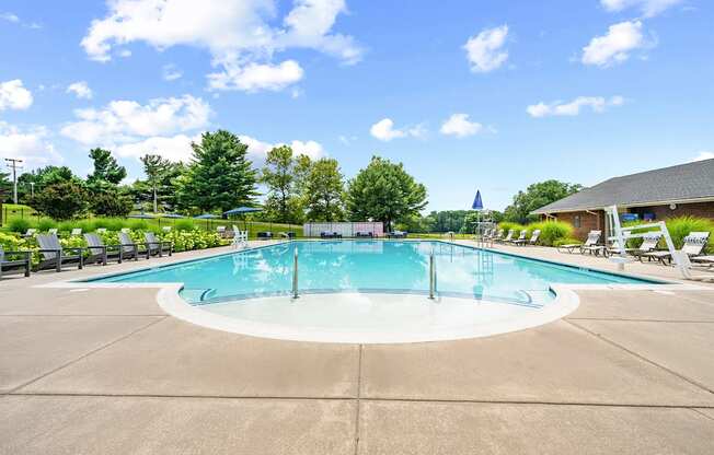 A large outdoor swimming pool surrounded by trees and a building.