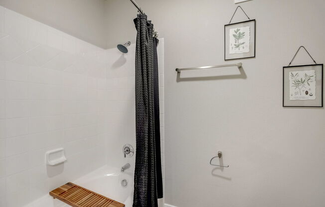 A bathroom with a white tub and a black shower curtain.