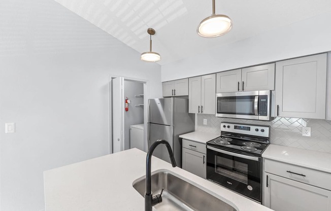 A kitchen with white cabinets and a stainless steel sink.