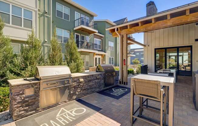 a patio with a grill and a bar with chairs