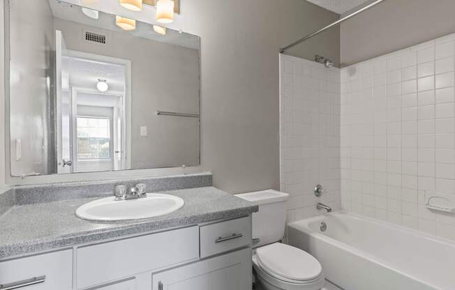 A bathroom with a white tub, sink, and toilet.
