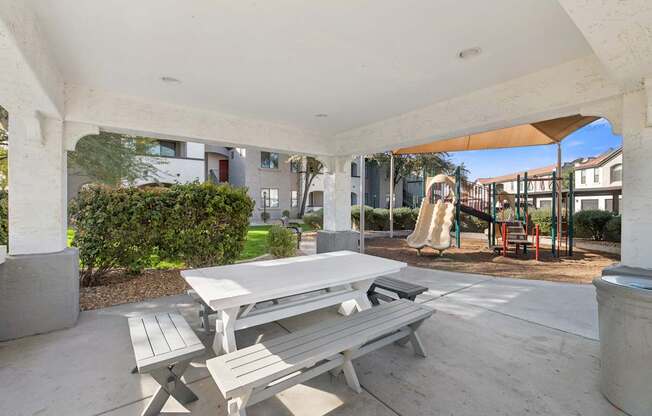 A concrete patio with a table and benches.