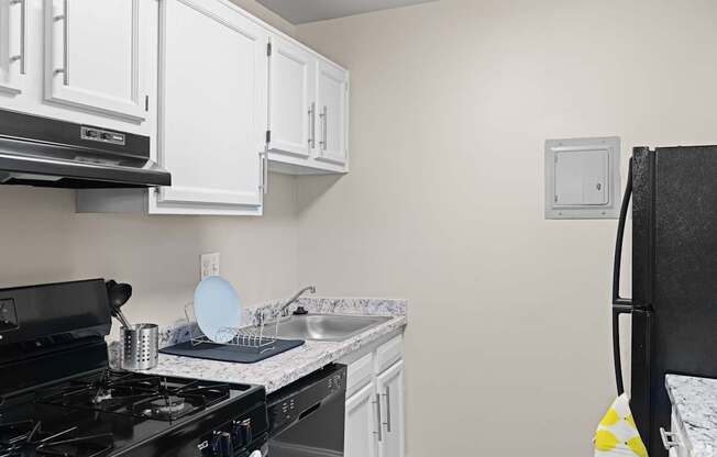 A kitchen with a black stove top oven and white cabinets.