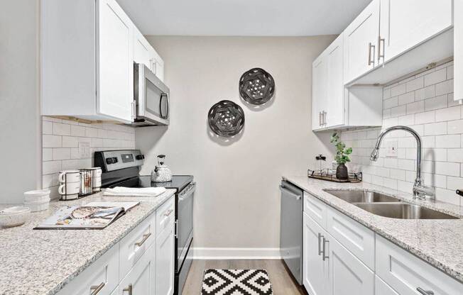 a kitchen with white cabinets and a black and white rug