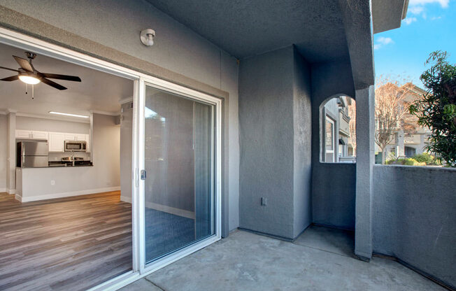 a patio with a sliding glass door and a kitchen in the background