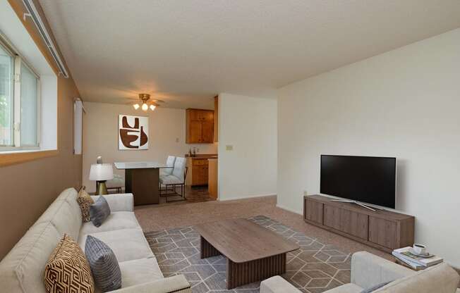 a living room with a couch and a television. Fargo, ND Country Club Apartments