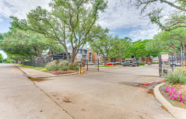 A tree-lined street with a sidewalk and a fence.